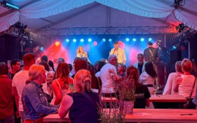 In einem beleuchteten Festzelt feiern viele Menschen