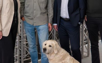 Drei Männer, eine Frau und ein Hund stehen als Gruppenbild gemeinsam in einer Traversenhalle