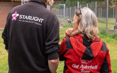 Ein Mann mit dem Aufdruck Starlight auf dem Rücken und eine Frau mit dem Aufdruck Gut Aidebachl auf dem Rücken stehen nebeneinander 