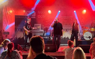 Band spielt auf der Bühne mit tanzenden Personen im Vordergrund  
