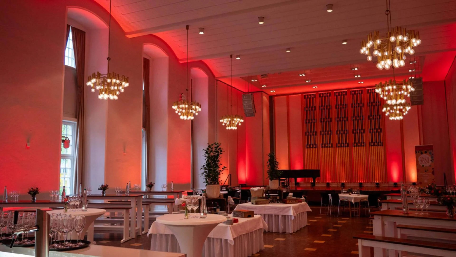 Saal mit roter Ambientebeleuchtung und gedeckten Tischen