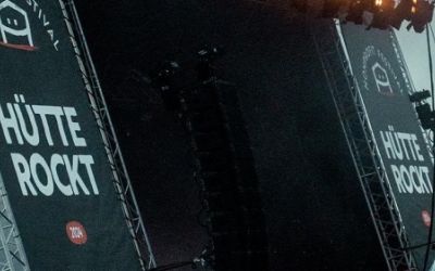 Seitlicher Blick auf die Eventbühne des Festivals Hütte Rockt und Publikum davor.